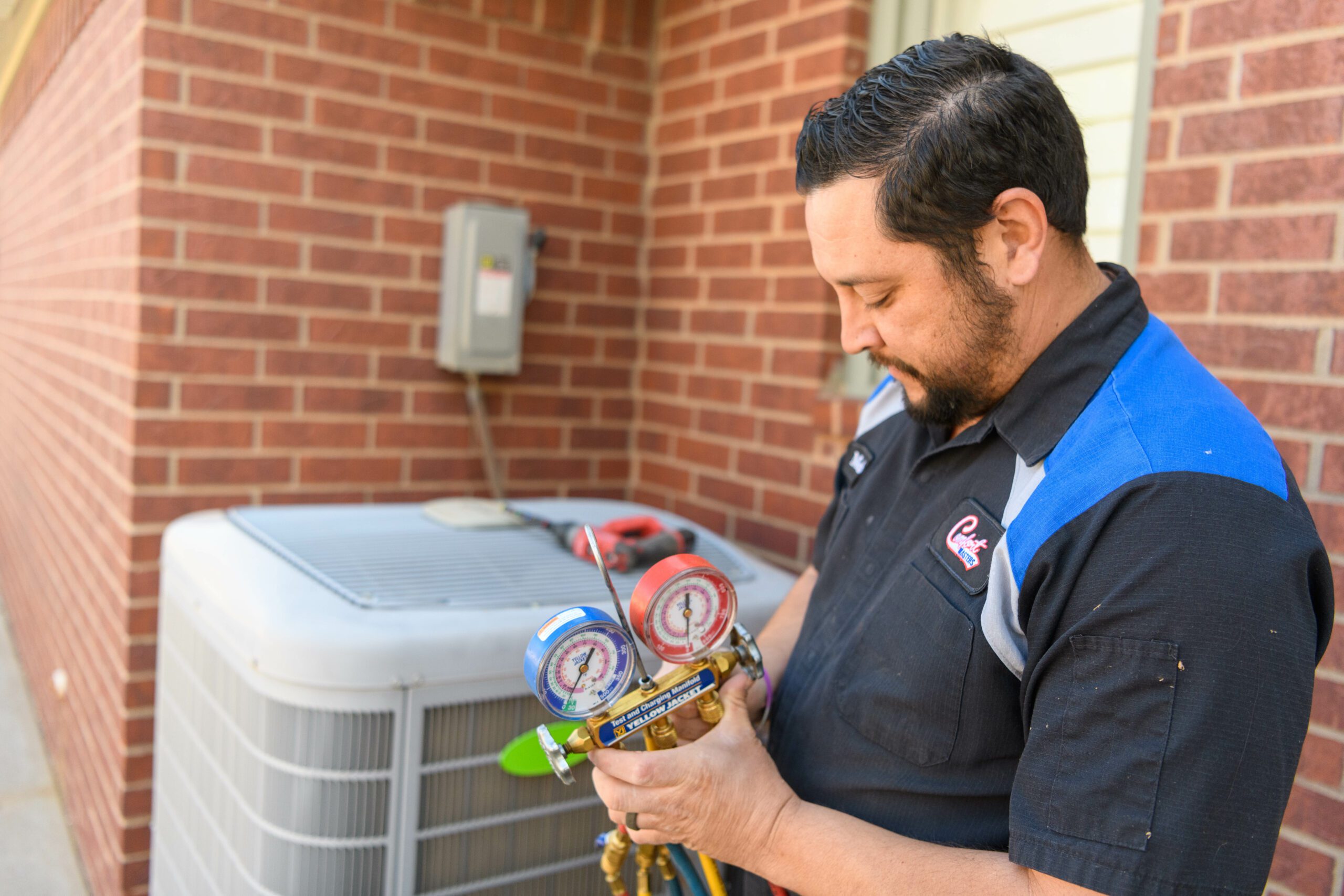 Man working with gauges in front of AC unit